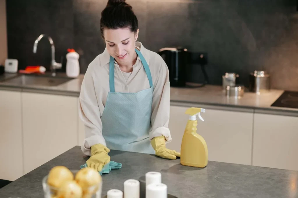 A-professional-cleaner-wiping-down-a-kitchen-counter-during-a-residential-house-cleaning.webp