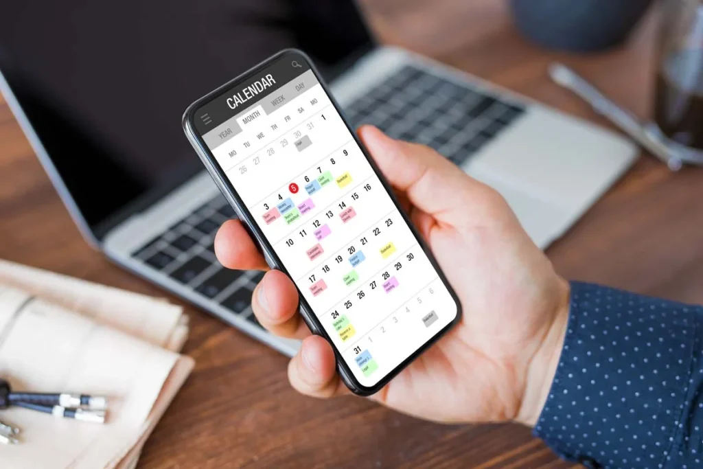 Hands holding a smartphone showing a digital calendar app to schedule a cleaning service