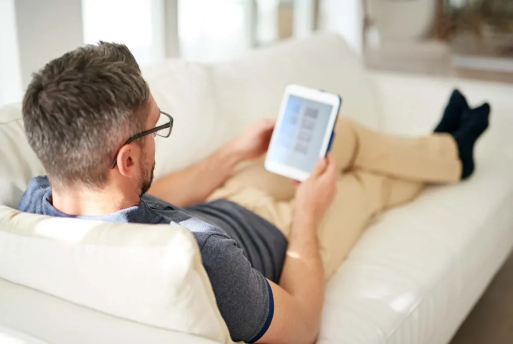 Homeowner using a laptop on the couch to request a house cleaning quote online