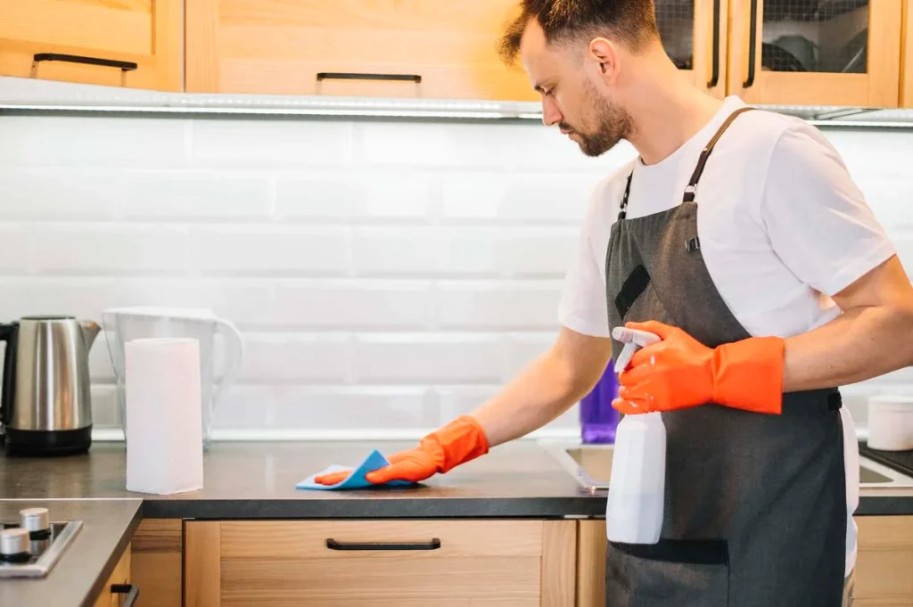 House cleaner actively wiping down a kitchen counter