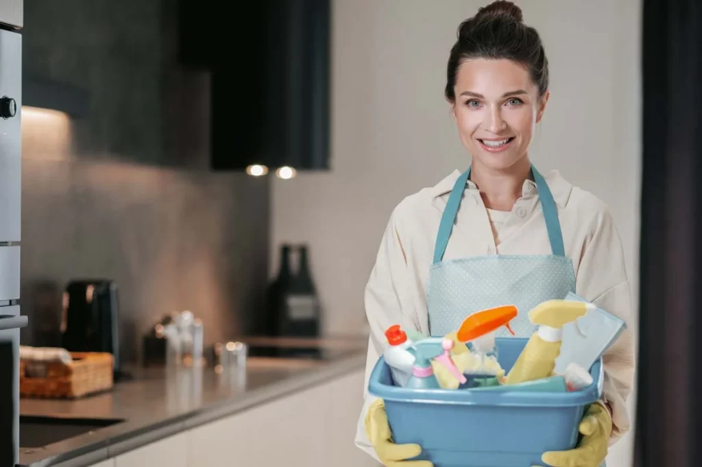 Friendly professional cleaner at a client's home with cleaning supplies